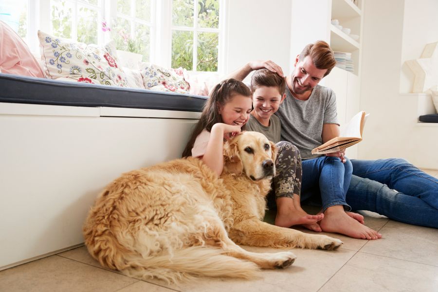 padres y su hija sentados junto a su perro en el suelo de su casa